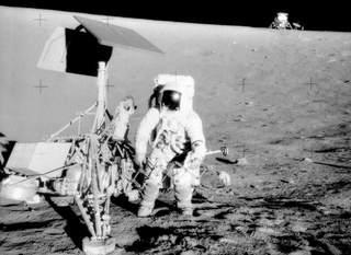 Conrad standing next to Surveyor 3, with the Lunar Module in the background. (NASA)